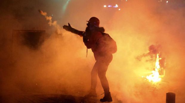 An anti-government protester throws back a tear gas canister against the riot police, during ongoing protests against the Lebanese central bank's governor and against the deepening financial crisis, at Hamra trade street, in Beirut, Lebanon, Tuesday, Jan. 14, 2020. Lebanese security forces lobbed tear gas at protesters who responded with rocks outside the country's central bank Tuesday, a violent turn after demonstrators returned to the streets following a weekslong lull. (AP Photo/Hussein Malla)