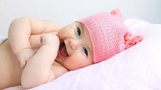 A small happy baby girl lying  on Front Wrapped in a towel.
