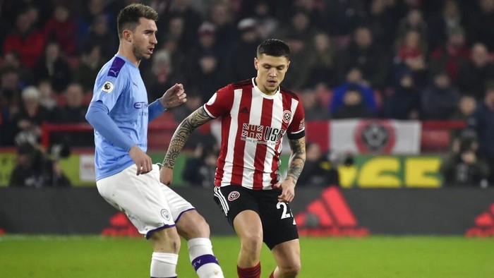 Manchester Citys Aymeric Laporte, left, and Sheffield Uniteds Muhamed Besic challenge for the ball during the English Premier League soccer match between Sheffield United and Manchester City at Bramall Lane in Sheffield, England, Tuesday, Jan. 21, 2020. (AP Photo/Rui Vieira)