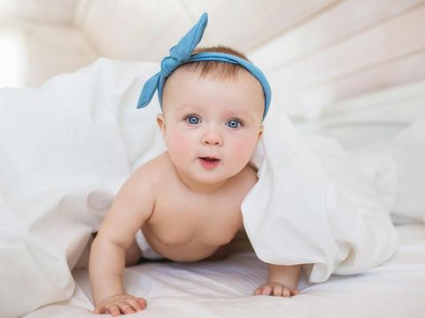 Portrait of smiling little baby in a diaper under a blanket on a bed