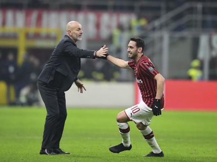 AC Milans Turkish forward Hakan Calhanoglu celebrates scoring his teams second goal with AC Milans Italian head coach Stefano Pioli during the Italian Cup (Coppa Italia) quarter final football match AC Milan vs Torino on January 28, 2020 at San Siro stadium in Milan. (Photo by MIGUEL MEDINA / AFP)