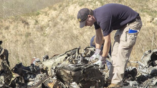 In this image taken Monday, Jan. 27, 2020, and provided by the National Transportation Safety Board, NTSB investigators Adam Huray, foreground, and Carol Hogan examine wreckage as part of the NTSB’s investigation of a helicopter crash near Calabasas, Calif. The Sunday, Jan. 26 crash killed former NBA basketball player Kobe Bryant, his 13-year-old daughter, Gianna, and seven others (James Anderson/National Transportation Safety Board via AP)