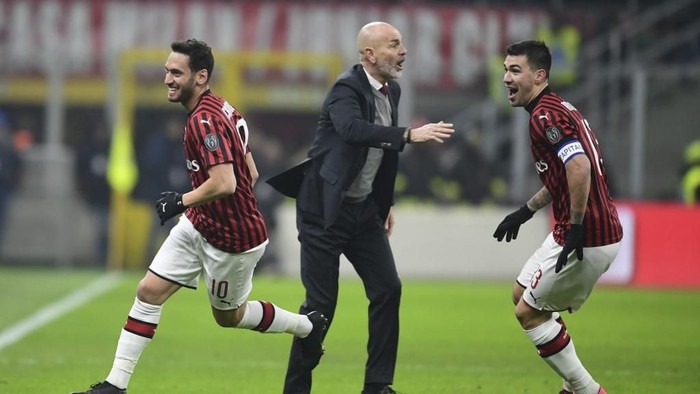 AC Milans Turkish forward Hakan Calhanoglu (L) celebrates scoring his teams second goal with AC Milans Italian head coach Stefano Pioli (C) and AC Milans Italian defender Alessio Romagnoli during the Italian Cup (Coppa Italia) quarter final football match AC Milan vs Torino on January 28, 2020 at San Siro stadium in Milan. (Photo by MIGUEL MEDINA / AFP)