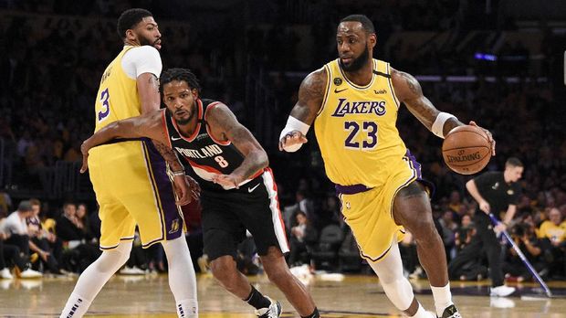 Los Angeles Lakers forward LeBron James, right, handles the ball while Anthony Davis, left, sets a screen on Portland Trail Blazers forward Trevor Ariza during the second half of an NBA basketball game in Los Angeles, Friday, Jan. 31, 2020. (AP Photo/Kelvin Kuo)