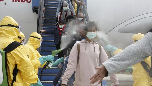 In this photo released by Indonesian Foreign Ministry, Indonesian people who arrived from Wuhan, China, are sprayed antiseptic at Hang Nadim Airport in Batam, Indonesia Sunday, Feb. 2, 2020. Indonesians evacuated from Wuhan, the Chinese city at the center of a deadly virus outbreak, were transported to a quarantine zone on a remote island at the edge of the South China Sea, shortly after landed on Batam, an island near Singapore on Sunday morning. (Indonesian Foreign Ministry via AP)