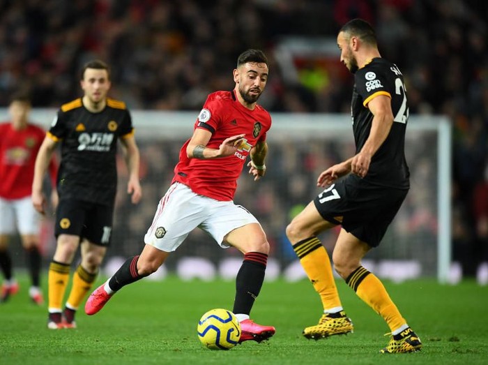 MANCHESTER, ENGLAND - FEBRUARY 01: Romain Saiss of Wolverhampton Wanderers is challenged by Bruno Fernandes of Manchester United during the Premier League match between Manchester United and Wolverhampton Wanderers at Old Trafford on February 01, 2020 in Manchester, United Kingdom. (Photo by Clive Mason/Getty Images)