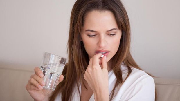 Sick young woman suffering from migraine or headache hold glass of water and painkiller medicine considering having pill, unwell millennial girl feel sad pondering taking antidepressant medication