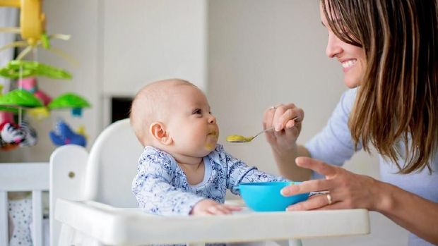 Cute little baby boy, eating mashed vegetables for lunch, mom feeding him, sweet toddler boy, smiling