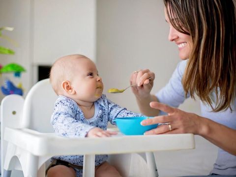 Cute little baby boy, eating mashed vegetables for lunch, mom feeding him, sweet toddler boy, smiling