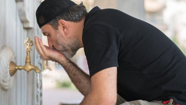 Istanbul, Turkey - April 07, 2012: Man performing ablution. Ablution is a ritual act, where the person washes himself/herself in order to get ready for the prayer. Image taken during midday at the fountains next to Sultanahmet Mosque in Istanbul.