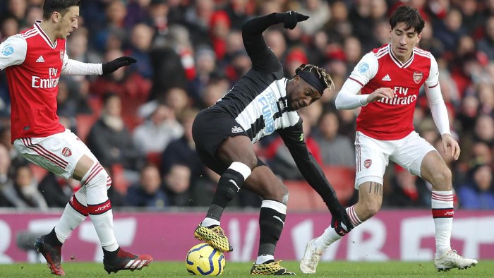 Arsenals Hector Bellerin, right, challenges for the ball with Newcastles Allan Saint-Maximin, center, during the English Premier League soccer match between Arsenal and Newcastle at the Emirates Stadium in London, Sunday, Feb. 16, 2020.(AP Photo/Frank Augstein)