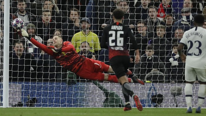 Leipzigs goalkeeper Peter Gulacsi, left, dives to save on a free kick by Tottenhams Erik Lamela during a first leg, round of 16, Champions League soccer match between Tottenham Hotspur and Leipzig at the Tottenham Hotspur Stadium in London, England, Wednesday Feb. 19, 2020. (AP Photo/Matt Dunham)