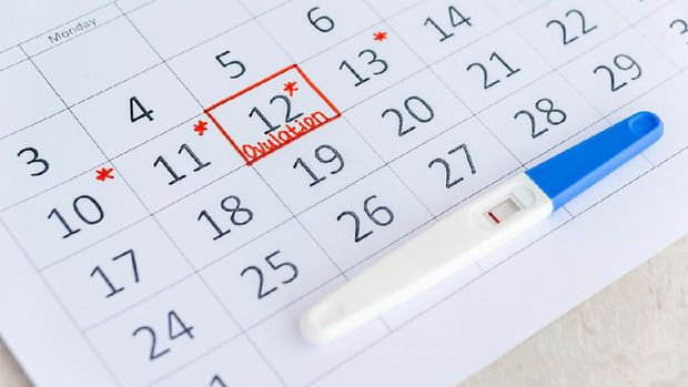 Negative pregnancy test with circling date in calendar. Planning of pregnancy, trying to have baby. Top view.