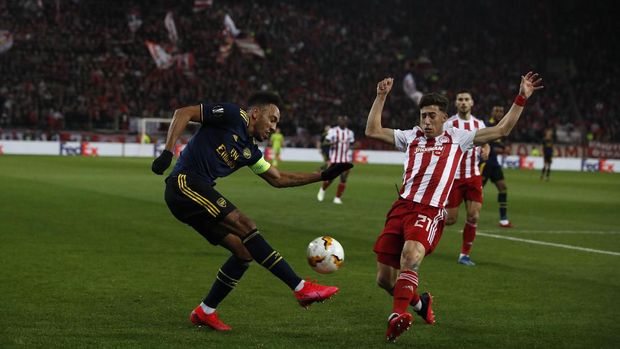 Arsenal's Pierre-Emerick Aubameyang, left, is challenged by Olympiakos' Kostas Tsimikas during the Europa League round of 32, first leg, soccer match between Olympiakos and Arsenal at the Georgios Karaiskakis stadium in Piraeus port, near Athens, Thursday, Feb. 20, 2020. (AP Photo/Thanassis Stavrakis)