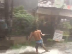 Ditarik Motor, Pria Ini Asyik Surfing di Tengah Banjir