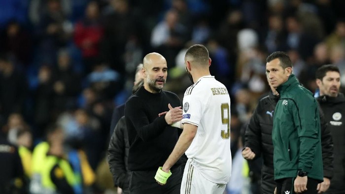 Manchester Citys head coach Pep Guardiola, front left, shakes hands with Real Madrids Karim Benzema at the end of the Champions League, round of 16, first leg soccer match between Real Madrid and Manchester City at the Santiago Bernabeu stadium in Madrid, Spain, Wednesday, Feb. 26, 2020. (AP Photo/Manu Fernandez)