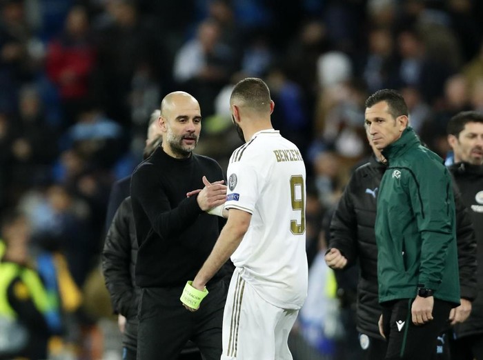 Manchester Citys head coach Pep Guardiola, front left, shakes hands with Real Madrids Karim Benzema at the end of the Champions League, round of 16, first leg soccer match between Real Madrid and Manchester City at the Santiago Bernabeu stadium in Madrid, Spain, Wednesday, Feb. 26, 2020. (AP Photo/Manu Fernandez)