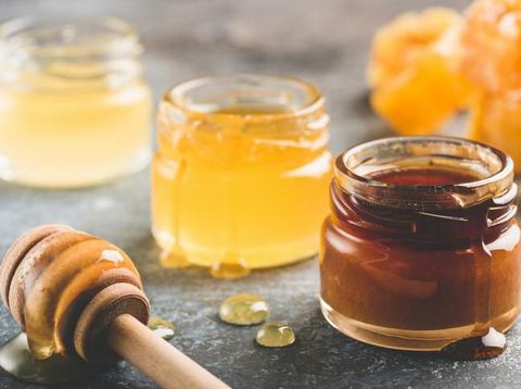 High resolution image of organic forest honey in a glass bowl with wooden honey dipper shot in studio on white background