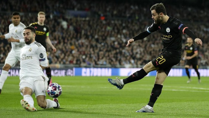 Real Madrids Dani Carvajal, left, tries to block a shot from Manchester Citys Bernardo Silva during the Champions League, round of 16, first leg soccer match between Real Madrid and Manchester City at the Santiago Bernabeu stadium in Madrid, Spain, Wednesday, Feb. 26, 2020. (AP Photo/Manu Fernandez)