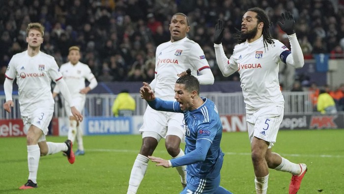 Juventus Cristiano Ronaldo goes down in the penalty box after contact with Lyons Jason Denayer, right, during a round of sixteen, first leg, soccer match between Lyon and Juventus at the at the Lyon Olympic Stadium in Decines, outside Lyon, France, Wednesday, Feb. 26, 2020. (AP Photo/Laurent Cipriani)