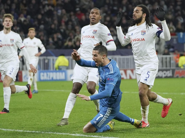 Juventus Cristiano Ronaldo goes down in the penalty box after contact with Lyons Jason Denayer, right, during a round of sixteen, first leg, soccer match between Lyon and Juventus at the at the Lyon Olympic Stadium in Decines, outside Lyon, France, Wednesday, Feb. 26, 2020. (AP Photo/Laurent Cipriani)
