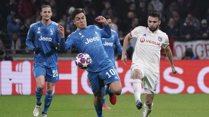 Juventus Paulo Dybala, center, and Lyons Leo Dubois, right, vie for the ball during a round of sixteen, first leg, soccer match between Lyon and Juventus at the at the Lyon Olympic Stadium in Decines, outside Lyon, France, Wednesday, Feb. 26, 2020. (AP Photo/Laurent Cipriani)