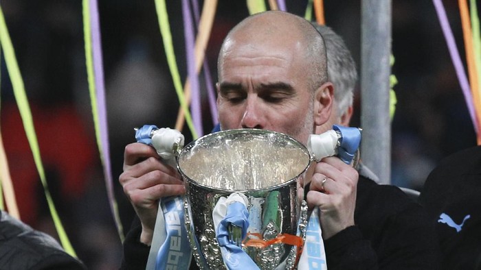 Manchester Citys head coach Pep Guardiola kisses the trophy after winning the League Cup soccer match final with a 2-1 score against Aston Villa, at Wembley stadium, in London, England, Sunday, March 1, 2020. (AP Photo/Ian Walton)