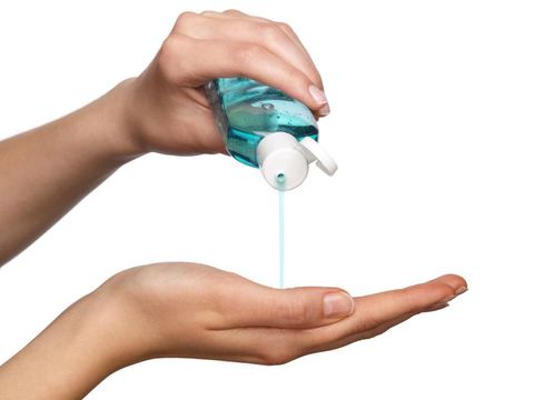 Closeup of a hand pouring sanitizer in the other, isolated on white background.