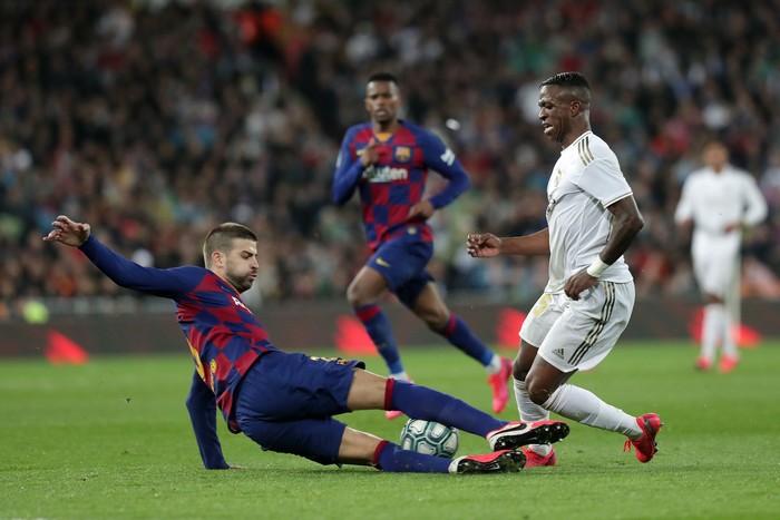 MADRID, SPAIN - MARCH 01: Gerard Pique of FC Barcelona tackles Vinicius Junior of Real Madrid during the Liga match between Real Madrid CF and FC Barcelona at Estadio Santiago Bernabeu on March 01, 2020 in Madrid, Spain. (Photo by Gonzalo Arroyo Moreno/Getty Images)