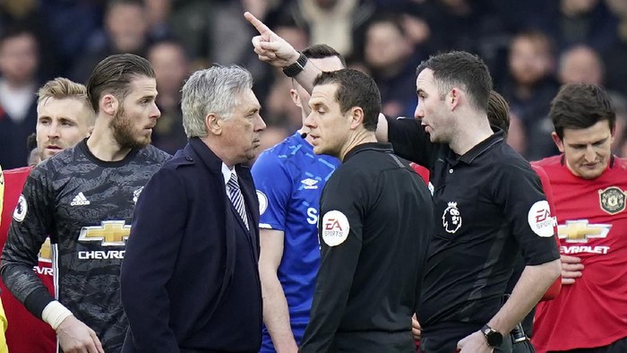 Referee Christopher Kavanagh gestures to Evertons manager Carlo Ancelotti, center left, after showing him a red card during the English Premier League soccer match between Everton and Manchester United at Goodison Park in Liverpool, England, Sunday, March 1, 2020. (AP Photo/Jon Super)