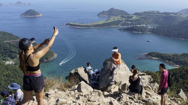 Tren Olahraga Hiking untuk Hindari Virus Corona di Hong Kong In this picture taken on February 29, 2020, hikers take pictures on High Junk Peak overlooking Clearwater Bay in the Tsuen Kwan O area of Hong Kong. - Remote hiking trails are offering Hong Kongers an open-air escape from the coronavirus fears that have engulfed the densely-populated city and triggered the closure of public facilities and schools. (Photo by Yan ZHAO / AFP) / To go with AFP story Hong Kong-health-virus-lifestyle by Yan Zhao