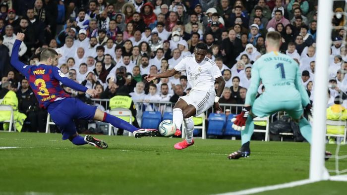 Real Madrids Vinicius Junior, center, scores his sides opening goal past Barcelonas goalkeeper Marc-Andre ter Stegen, right, as Barcelonas Gerard Pique tries to block during the Spanish La Liga soccer match between Real Madrid and Barcelona at the Santiago Bernabeu stadium in Madrid, Spain, Sunday, March 1, 2020. (AP Photo/Manu Fernandez)