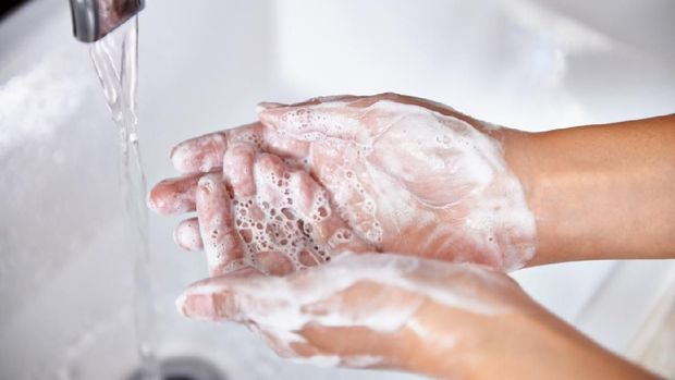 A cropped shot of a young woman washing her hands in her bathroom