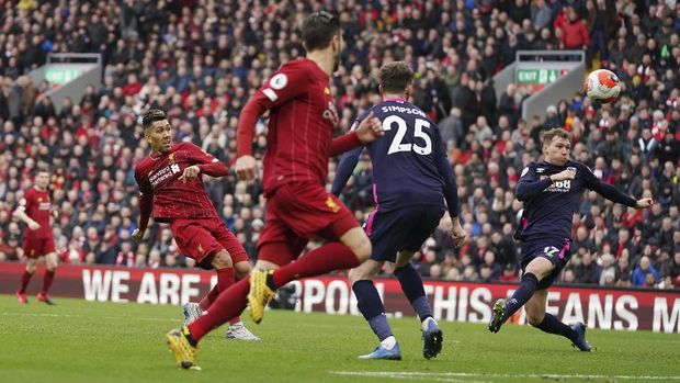 Liverpool's Roberto Firmino, left, attempts a shot on goal during the English Premier League soccer match between Liverpool and Bournemouth at Anfield stadium in Liverpool, England, Saturday, March 7, 2020. (AP Photo/Jon Super)