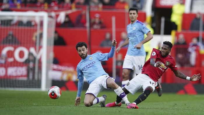 Manchester Citys Bernardo Silva, left, and Manchester Uniteds Fred compete for the ball during the English Premier League soccer match between Manchester United and Manchester City at Old Trafford in Manchester, England, Sunday, March 8, 2020. (AP Photo/Dave Thompson)