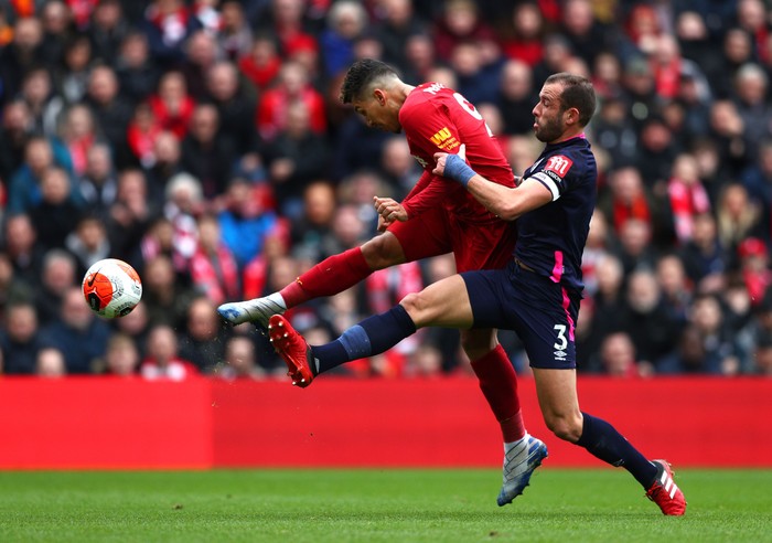 LIVERPOOL, ENGLAND - MARCH 07: Roberto Firmino of Liverpool shoots while under pressure from Steve Cook of AFC Bournemouth during the Premier League match between Liverpool FC and AFC Bournemouth  at Anfield on March 07, 2020 in Liverpool, United Kingdom. (Photo by Jan Kruger/Getty Images)