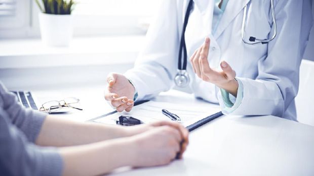 Close up of doctor and  patient  sitting at the desk near the window in hospital