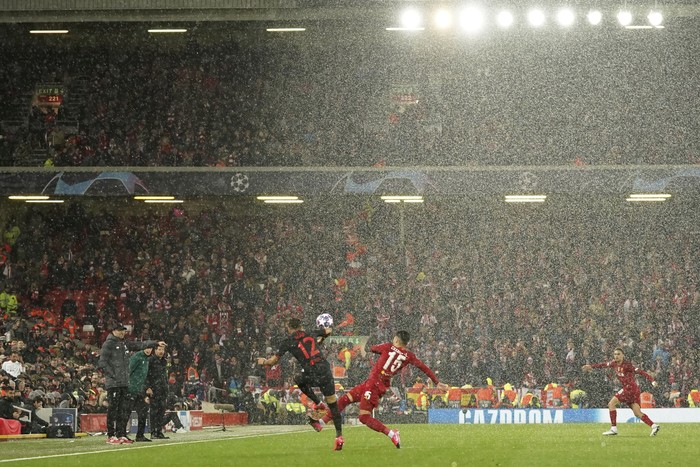 Atletico Madrids Renan Lodi, left, fights for the ball with Liverpools Alex Oxlade-Chamberlain under heavy hail during a second leg, round of 16, Champions League soccer match between Liverpool and Atletico Madrid at Anfield stadium in Liverpool, England, Wednesday, March 11, 2020. (AP Photo/Jon Super)