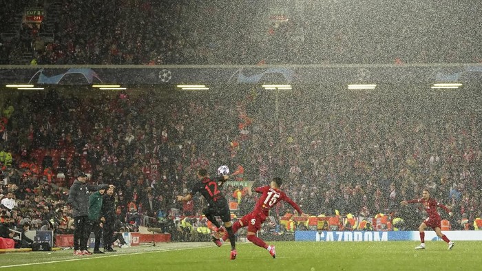 Atletico Madrids Renan Lodi, left, fights for the ball with Liverpools Alex Oxlade-Chamberlain under heavy hail during a second leg, round of 16, Champions League soccer match between Liverpool and Atletico Madrid at Anfield stadium in Liverpool, England, Wednesday, March 11, 2020. (AP Photo/Jon Super)