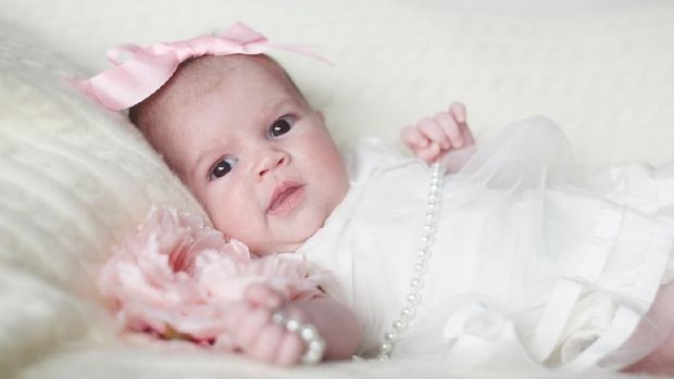 Newborn baby girl in fashionable dress with flower and pearl beads