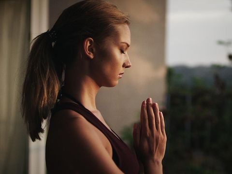 Namaste gesture close up photo, young attractive woman practicing yoga, working out, wearing wrist bracelets and rings, indoor, yoga studio, behind the shoulder view. Contemplation concept