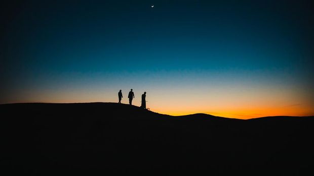 Arabs, Middle East, Culture - Three Arab men walking behind each other on the sand dunes