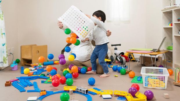 Adorable blonde toddler building pyramid using hoops around lots of toys at kindergarten