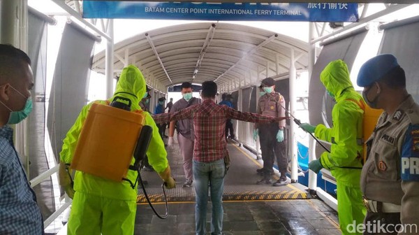 Petugas menyemprotkan disinfektan ke TKI yang tiba di Pelabuhan Internasional Batam (Agus Siagian/detikcom)