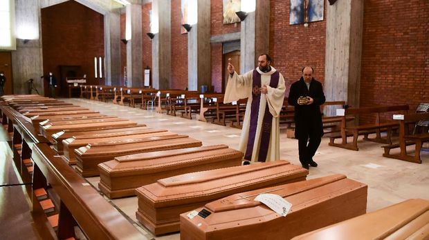 Memberi Doa Korban Corona di Italia Priest Don Marcello gives a blessing to the coffins of deceased people inside the church of San Giuseppe in Seriate, on March 28, 2020. (Photo by Piero CRUCIATTI / AFP)