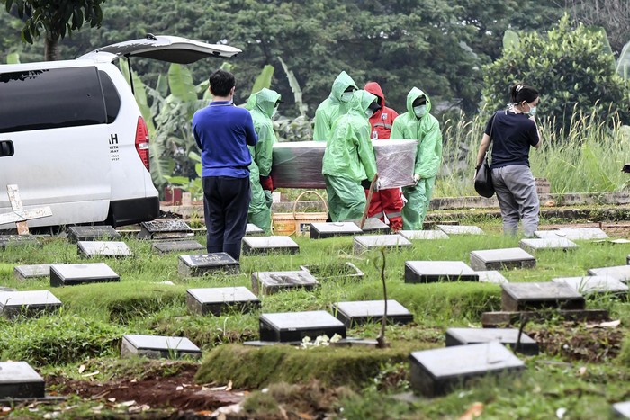 Petugas pemakaman menurunkan peti jenazah pasien COVID-19 di TPU Pondok Ranggon, Jakarta, Senin (30/3/2020). Juru bicara pemerintah untuk penanganan COVID-19 Achmad Yurianto per Senin (30/3/2020) pukul 12.00 WIB menyatakan jumlah pasien positif COVID-19 di Indonesia telah mencapai 1.414  kasus, pasien yang telah dinyatakan sembuh sebanyak 75 orang, sementara kasus kematian bertambah delapan orang dari sebelumnya 114 orang menjadi 122 orang. ANTARA FOTO/Muhammad Adimaja/foc.