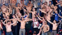 Di tribune stadion, panitia pelaksana juga tidak menerapkan aturan jaga jarak pada suporter. Penonton tetap duduk berdempetan, dan asyik bernyanyi. Terlihat suporter FC Minsk, bertelanjang dada dan tanpa masker mendukung tim tuan rumah. (Foto: Sergei GAPON / AFP)