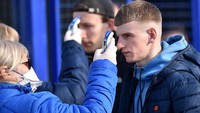 Pengecekan suhu tubuh dilakukan kepada para suporter kedua belah tim sebelum memasuki stadion. Hal itu dilakukan, tentu, untuk menghindari penyebaran virus corona. (Foto: Sergei GAPON / AFP)