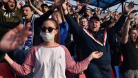 Muda mudi dan orang tua juga larut dalam euforia laga. Sebagian ada yang memakai masker, namun lebih banyak yang tanpa alat perlindungan diri saat menonton keseruan laga derbi. (Foto: Sergei GAPON / AFP)