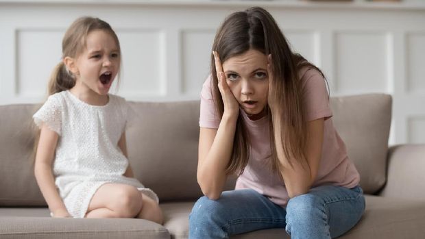 Stressed exhausted mother looking at camera feeling desperate about screaming stubborn kid daughter tantrum, upset annoyed mom tired of naughty difficult child girl misbehave yelling for attention